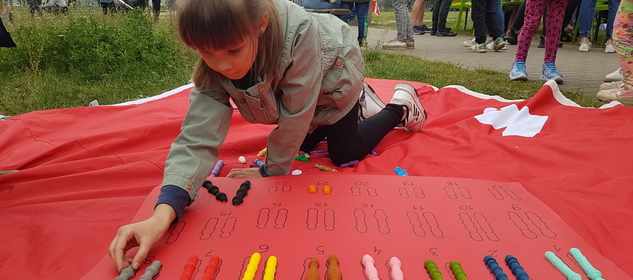 Dziewczynka na pikniku rodzinnym układa układankę z chromosomów